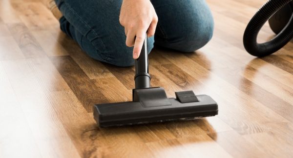 melhores empresas de polimento de parquet do Brasil - Uma pessoa limpa e lustra um piso de madeira com uma enceradeira