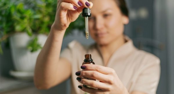 melhores homeopatas do Brasil - Uma mulher segura um remédio natural em uma pipeta.