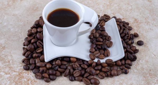 melhores cafés do Brasil - un taza de café, rodeada con granos de café