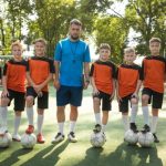 melhores escolinhas de futebol - un entrenador con su equipo de futbol infantil