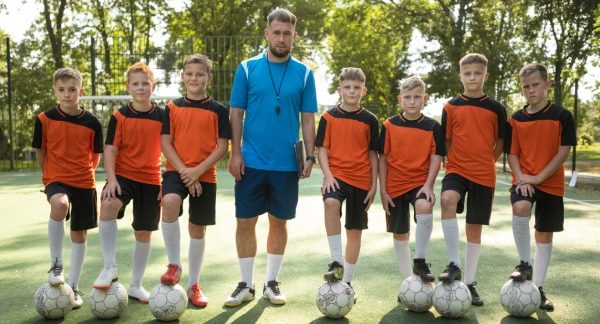 melhores escolinhas de futebol - un entrenador con su equipo de futbol infantil