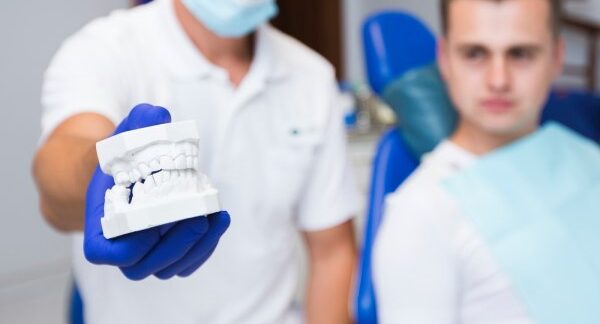 As melhores clínicas de prótese dentária do Brasil - Dentista mostrando ao paciente o molde dentário de seus dentes